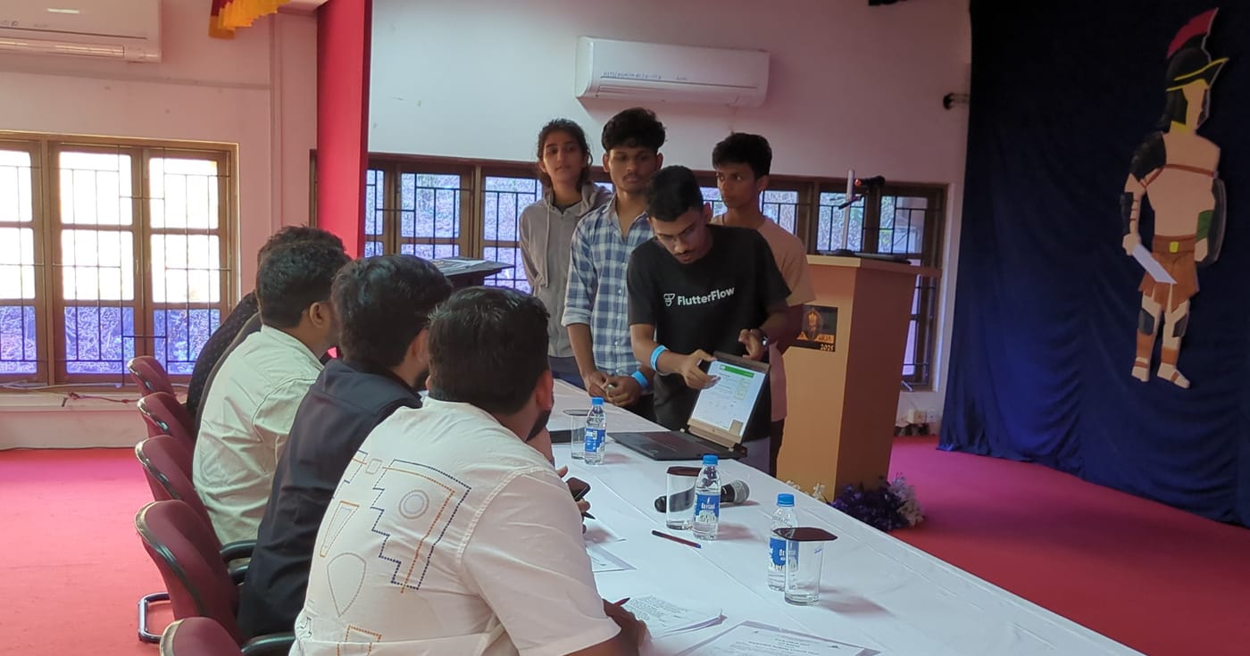 Jared Furtado demoing his team's project on a laptop to a panel of hackathon judges in Assagao, Goa